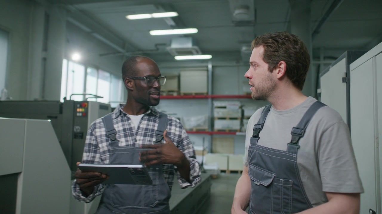 Diverse Workers Walking through Print Shop and Discussing Equipment Maintenance