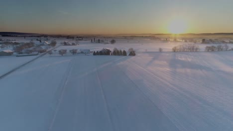 Vista-Aérea-Del-Amanecer-Temprano-En-La-Mañana-Después-De-Una-Caída-De-Nieve-En-El-Campo-Amish-Como-Senn-Por-S-Drone