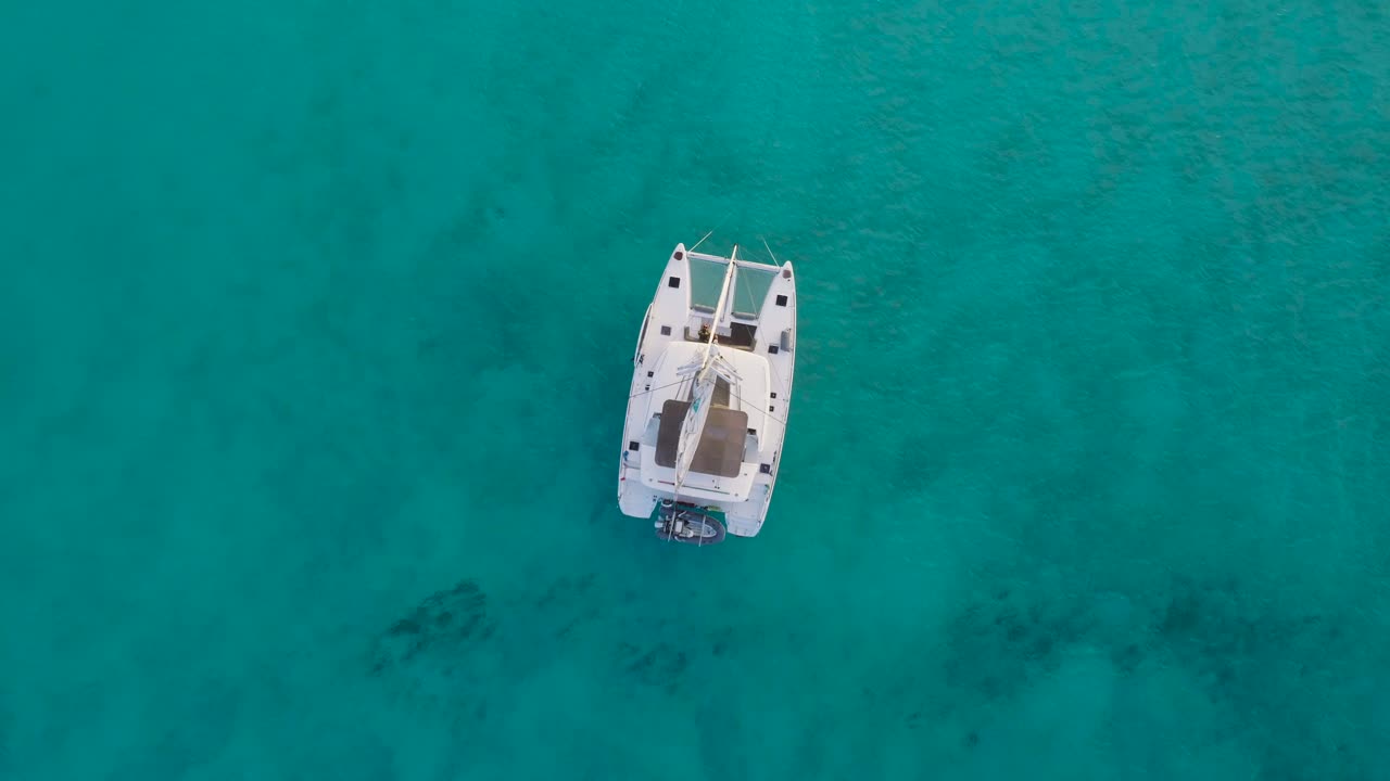 vista aérea de arriba hacia abajo de la isla desierta de las bahamas con un velero solitario y aguas claras