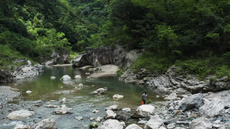 man walking on the rocky nizao river in dominican republic - drone shot