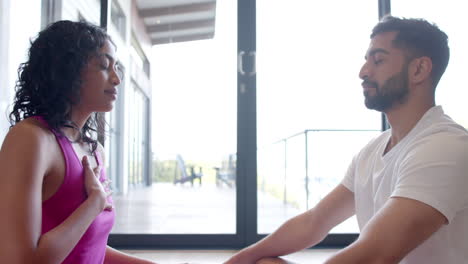 Biracial-couple-doing-yoga-and-meditating-at-home,-in-slow-motion