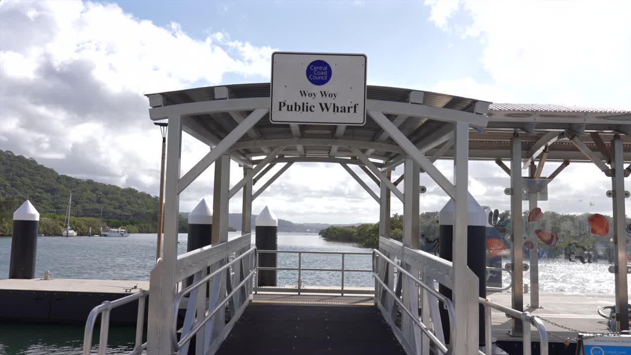 Eingangsstruktur mit Schild "Woy Woy Public Wharf" über einem Uferweg, Woy Woy, New South Wales, Australien