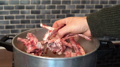 person picking up bones for bone broth out of soup pot, showing to camera