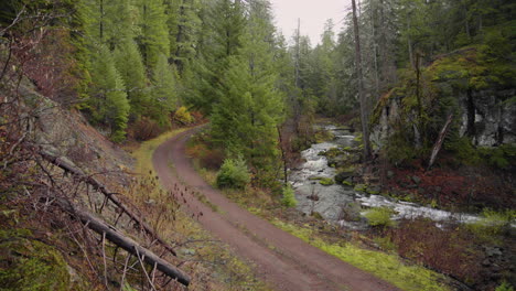 Pan-of-mountain-stream-with-winding-dirt-road