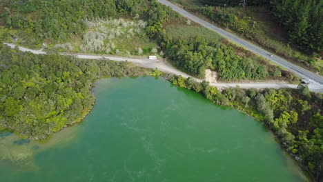 Toma-Aérea-De-Drones-De-Un-Lago-Humeante-Con-Carretera-Y-Rv-En-La-Selva-Tropical