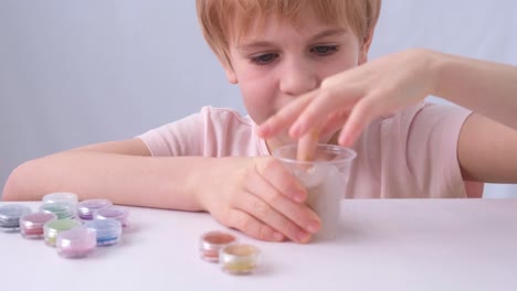 the child's hands are close-up. a child of primary school age takes the slime out of the jar. a slic of different colors. the child lays out the toy on the table in front of him. touch, emotion