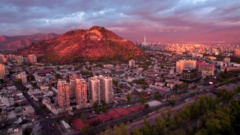 Panorámica-Aérea-De-La-Cima-De-Una-Colina-En-Medio-De-La-Ciudad-De-Santiago-Al-Atardecer