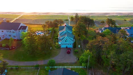 Scenic drone footage shows a Maine beach house overlooking the sunrise near waves. Sandy yard, ocean views, and windows make this prime real estate ideal for vacation or year-round coastal life