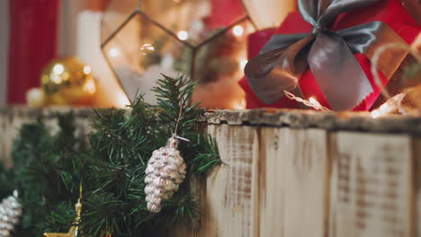 beautiful gift in the hands of men. new year's gift with a red ribbon, fir on the table. the man made it himself and is going to give for the holiday. beautiful background with fireplace.