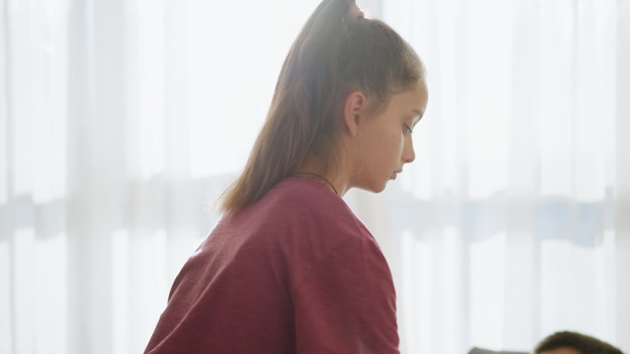Close-up of friend checking on sick boy lying on couch, with used tissues beside him, natural light filters through the window, creating a calm and caring atmosphere
