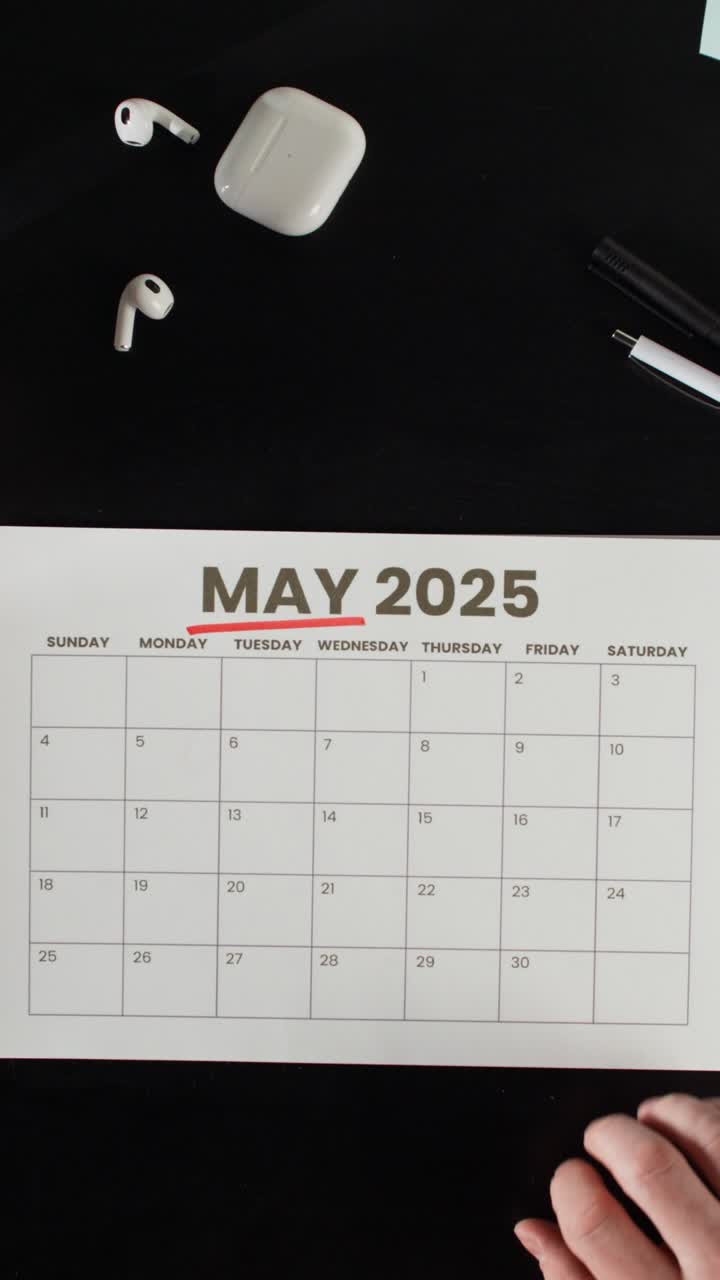 Person marking a date on a calendar for may 2025