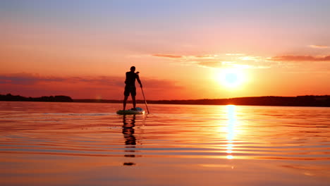 beautiful time and place for meditational paddle boarding. man floats on the sup board by the river at sunset. low angle view.