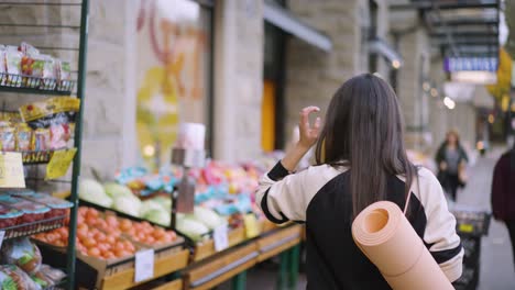 a woman walking towards the fruit stall towards in the local market.