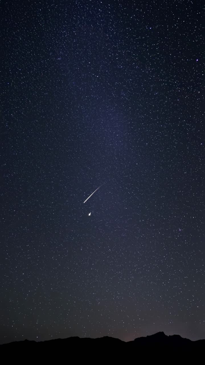 Shooting Stars Streaking Across a Dark Night Sky with Mountains