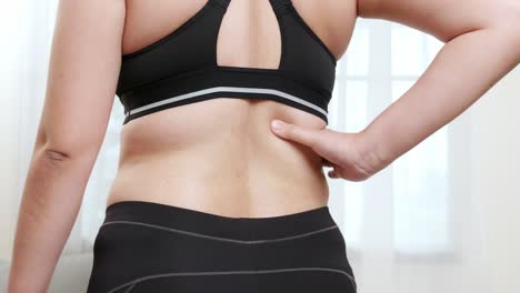 허리 통증으로 고통 받고 아픈 근육을 마사지하고 손으로 자기 마사지를하는 여성