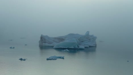 Wide-shot-of-iceberg-in-lake-covered-by-dense-fog-in-Iceland---Glacier-Lagoon-during-cloudy-day---Climate-change-and-global-warming