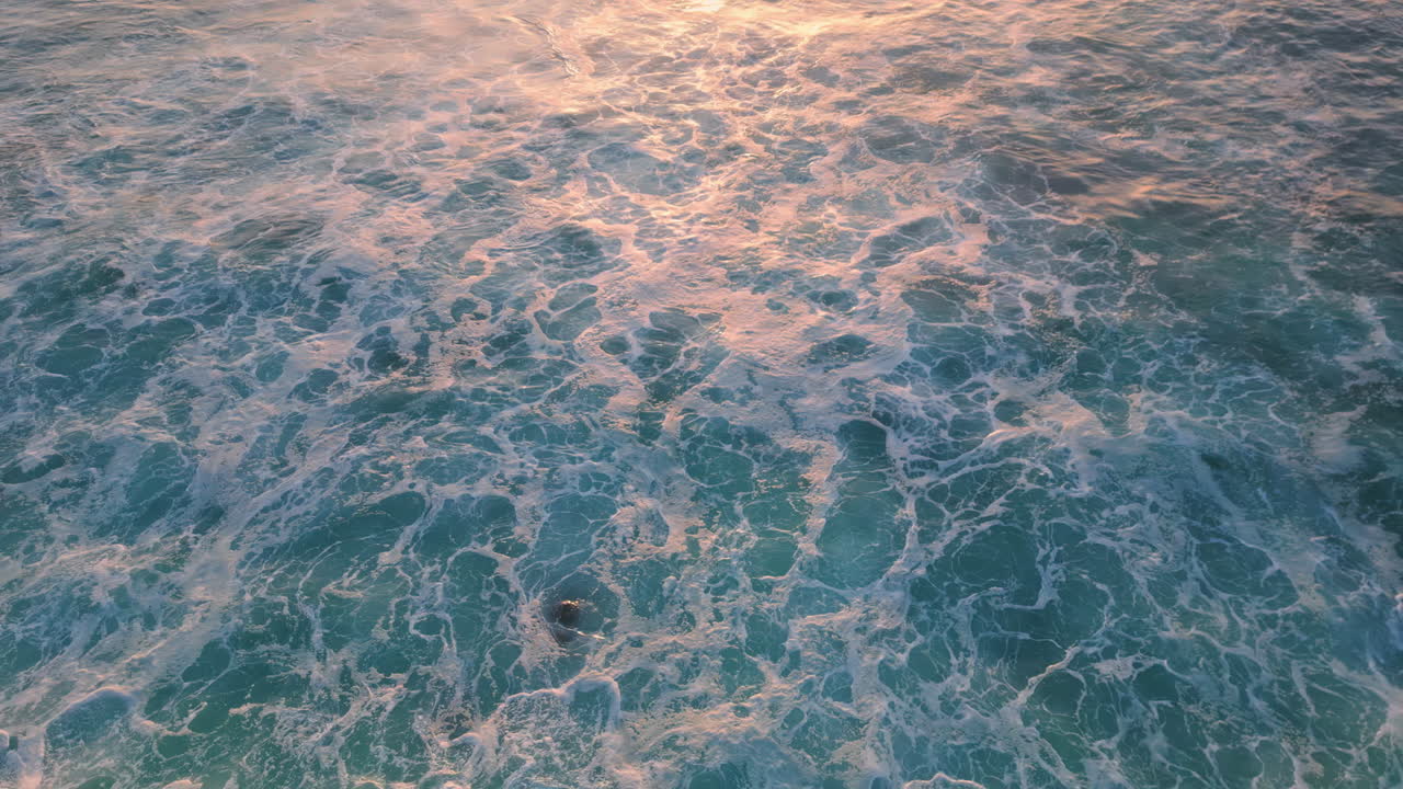 el agua de mar espumosa salpicando las piedras de la orilla del mar. las olas azules tormentosas aéreas rodando roca