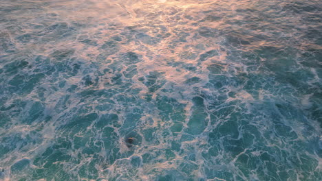 el agua de mar espumosa salpicando las piedras de la orilla del mar. las olas azules tormentosas aéreas rodando roca