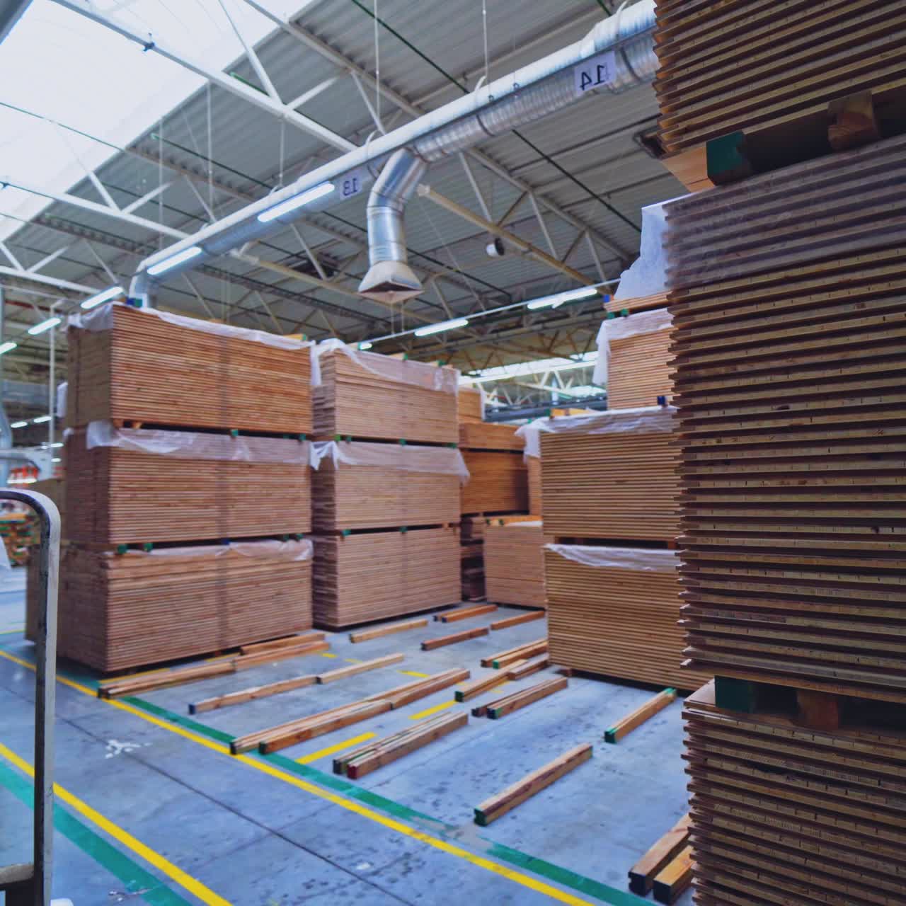Woodworking industry. Forklift cart putting stack of wooden boards on the floor. Modern factory of wood production. Camera motion back.