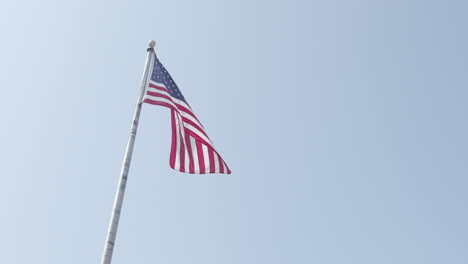 Eine-Amerikanische-Flagge-Weht-Auf-Einem-Fahnenmast-Gegen-Einen-Klaren-Himmel-In-Zeitlupe-Mit-Hoher-Bildrate