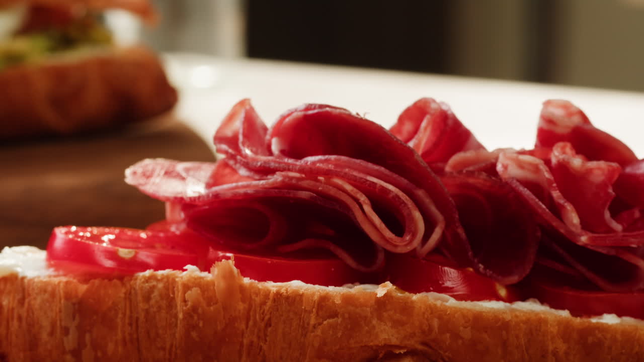 Making a Croissant Sandwich with Ham and Tomatoes