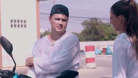 young man in black cap talks to pretty lady in white shirt