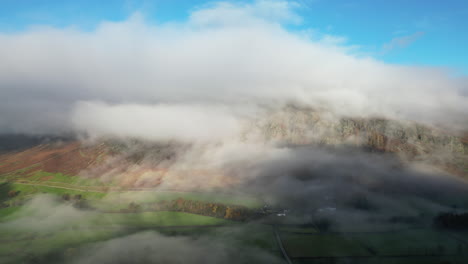 cloud shrouded mountains in early morning autumn sunlight with slow flight up towards cloud layer