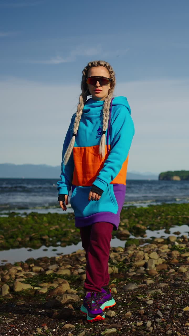 Young Woman in Colorful Hoodie Posing on a Rocky Beach