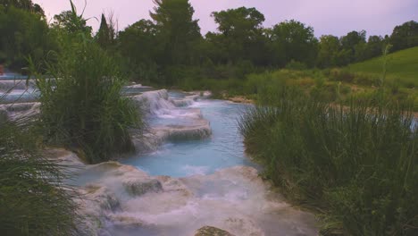 cinemagraph at the geothermal thermal hot springs bath and waterfall at saturnia, tuscany italy close to siena and grosseto by sunrise. cascate del mulino, scenic and famous place with blue steaming hot water in 4k uhd with fog.