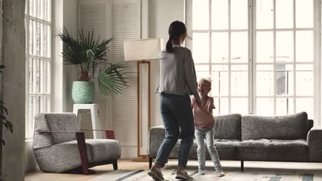 overjoyed elder and younger sisters jumping in living room.