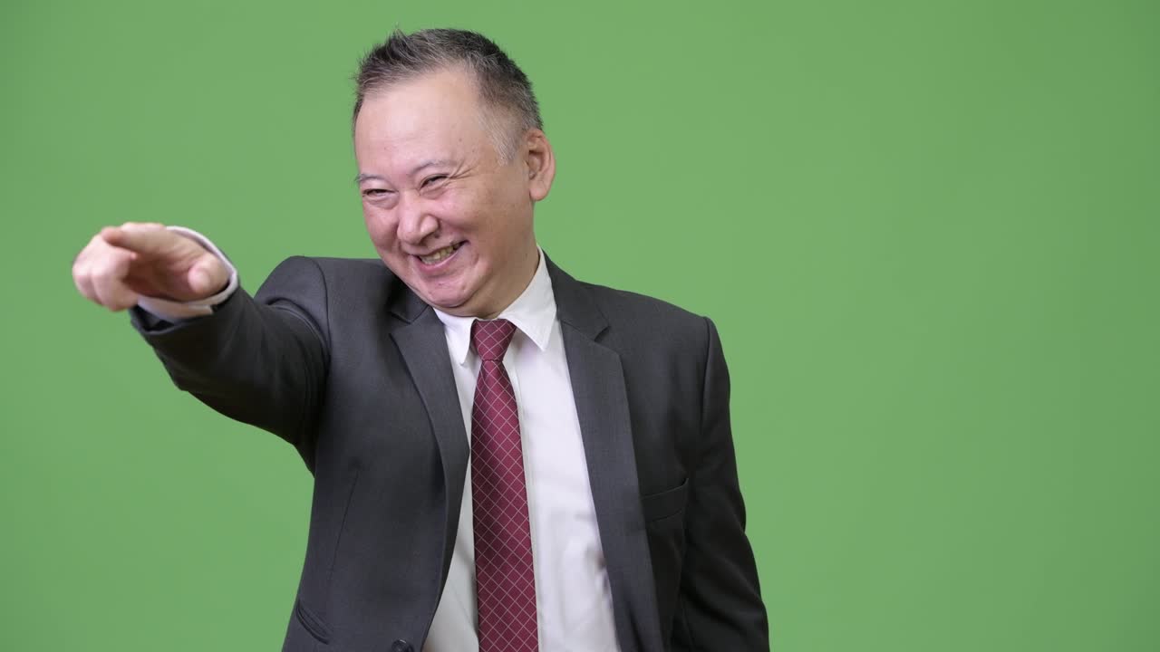 성숙하고 행복한 일본인 사업가 손가락을 가리키면서 미소 짓고