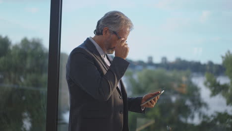 businessman looking at smartphone by window