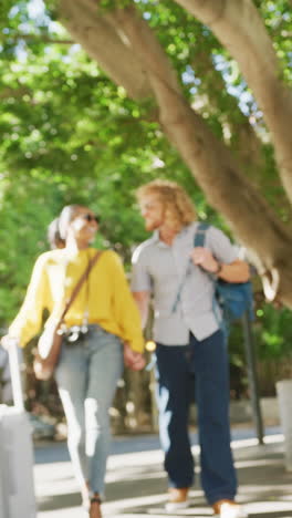 vertical video of happy diverse couple walking with luggage in city