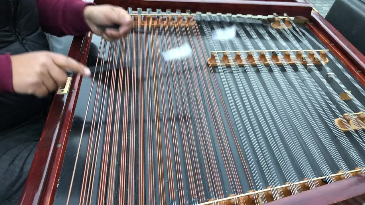 closeup hands of man, street musician playing a stringed musical instrument known as Hammered Dulcimer.