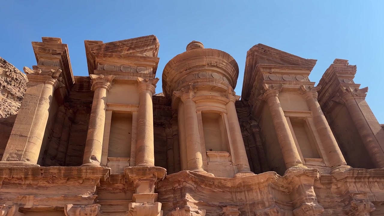 Splendide riprese dettagliate che catturano l'intricata lavorazione della pietra scolpita e i dettagli ornamentali sulla cima della magnifica facciata del Monastero, una delle strutture antiche più mozzafiato di Petra, Giordania.