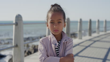 portrait angry little girl arms crossed looking serious naughty child on sunny seaside beach slow motion