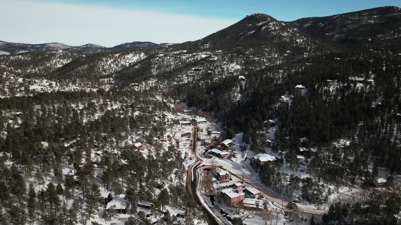 Downtown old historic Evergreen Colorado aerial drone cinematic winter fresh snow cold white scenic landscape near dam lake traffic driving around house ice skating late morning bluesky forward motion
