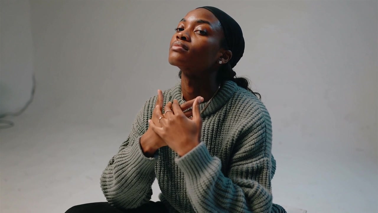 Starting hands at chin, woman in knit sweater crossing over chest, making poised pose showing rings