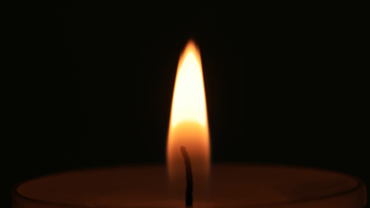 una singola candela bianca che brucia. scatto in studio da vicino, isolato su uno sfondo scuro