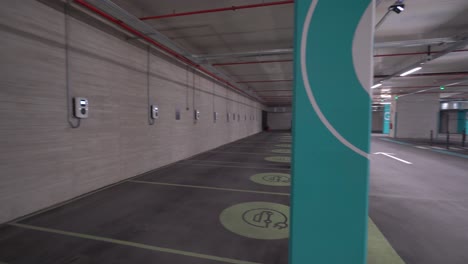 panorámica de izquierda a derecha: puntos de carga de vehículos eléctricos vacíos en un estacionamiento subterráneo