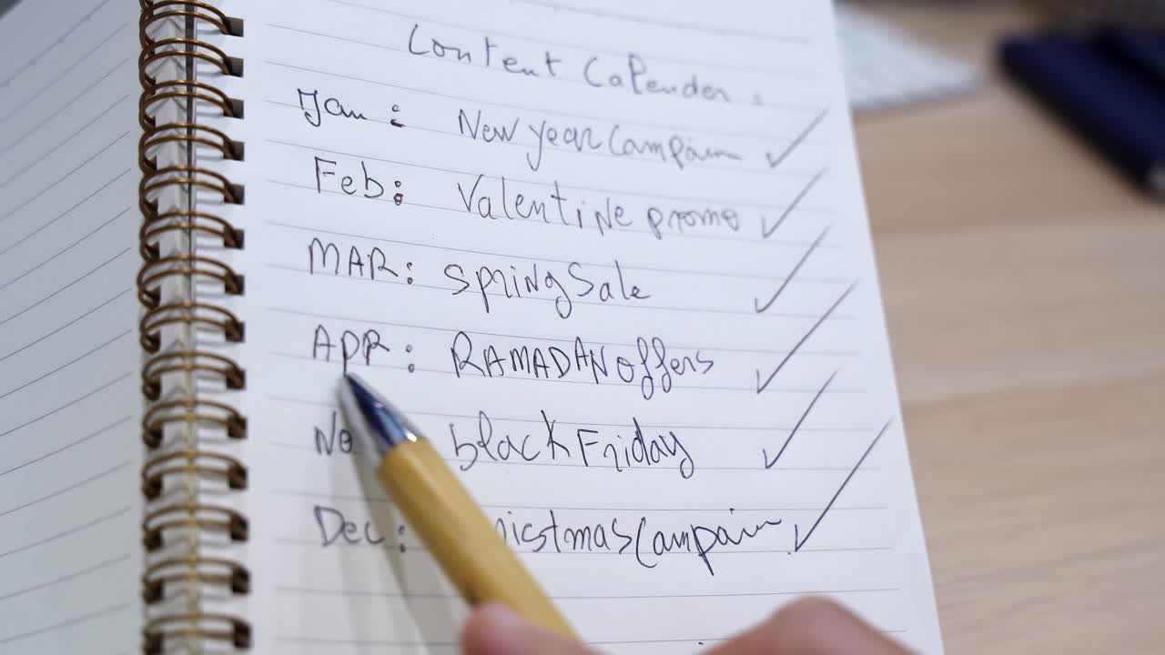 Close-up of a handwritten content calendar in a spiral notebook listing monthly campaigns including Ramadan, Black Friday, and Christmas, ideal for marketing and social media content