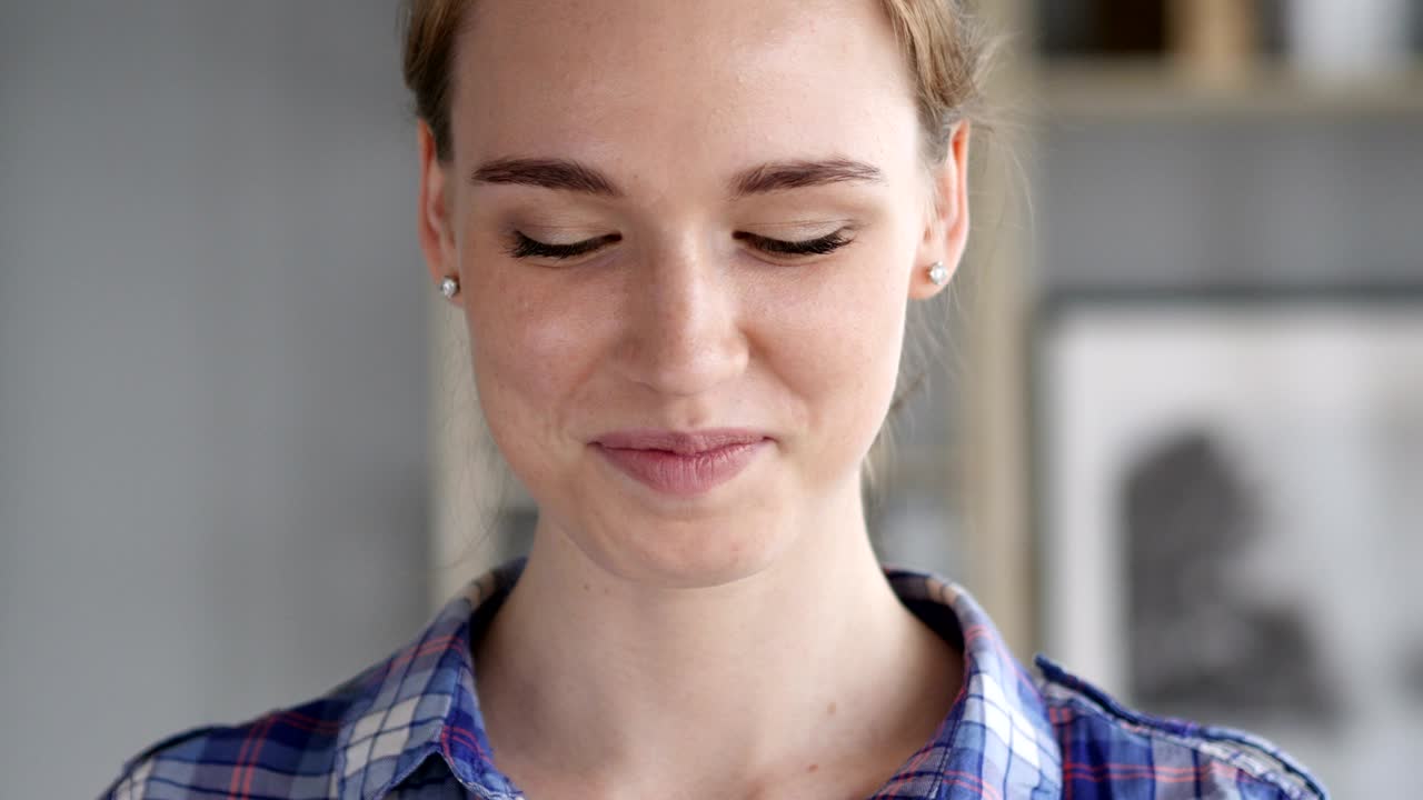 Thumbs Up by Young Woman at Work,  Looking at Camera