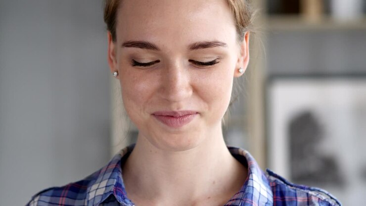 Thumbs Up by Young Woman at Work, Looking at Camera