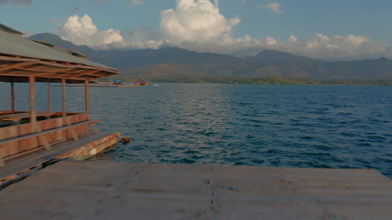 People enjoying sunset on rustic platform floating in sea off shore from West Bali