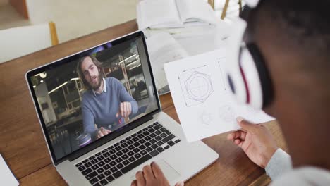 Estudiante-Universitario-Afroamericano-Sosteniendo-Notas-Mientras-Realiza-Una-Videollamada-En-Una-Computadora-Portátil-En-Casa