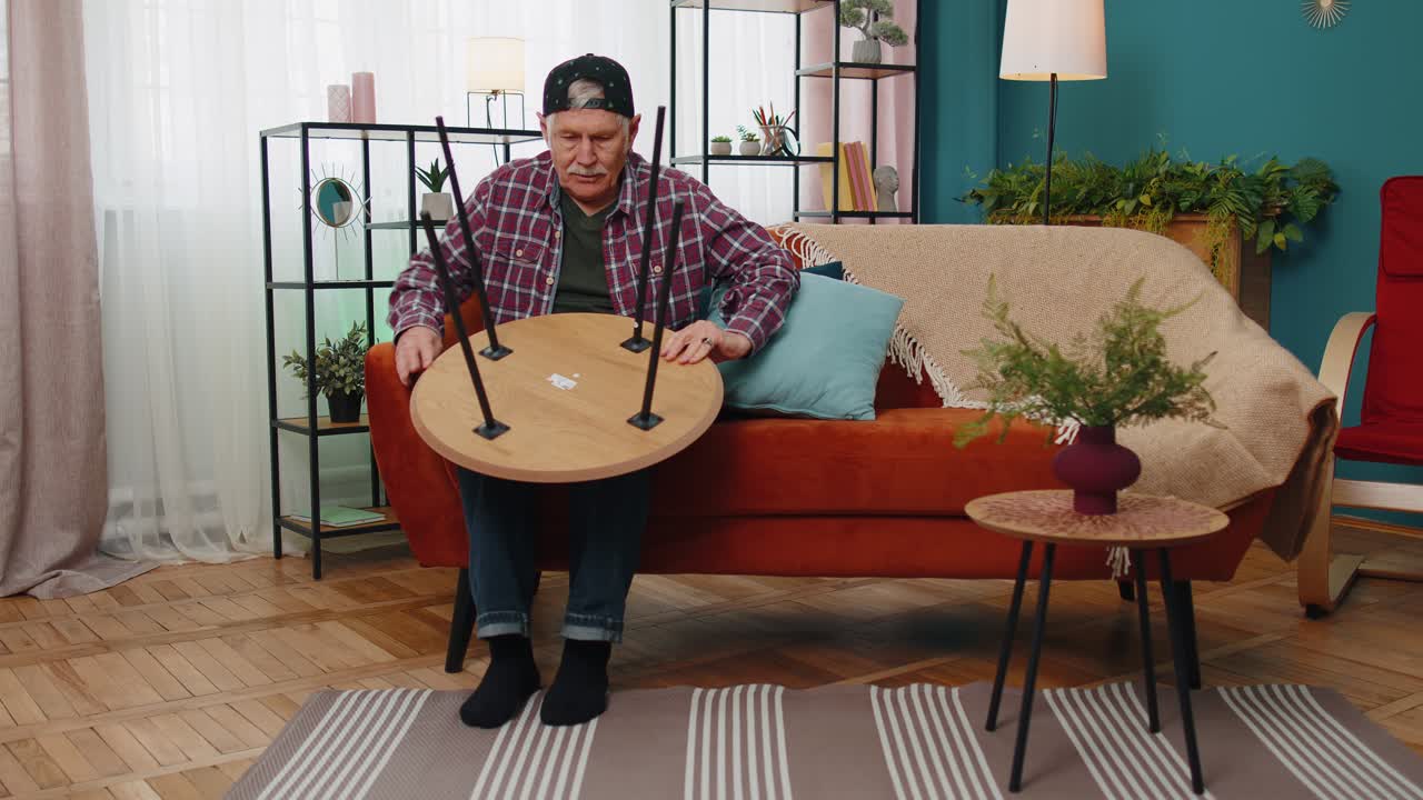 Senior elderly old grandfather finishing assembling furniture at home table collect repair fixing