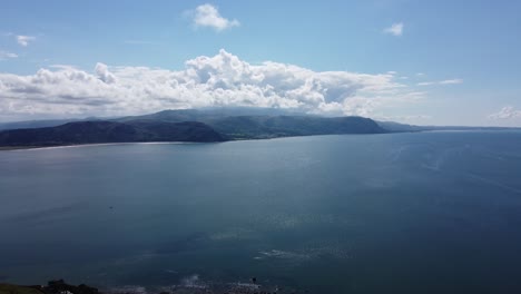 Impresionante-Vista-Al-Mar-Desde-Un-Dron-De-Alto-Vuelo-De-La-Costa-Norte-De-Gales-Y-Las-Montañas-De-Snowdonia-Al-Fondo-Desde-El-Gran-Orme