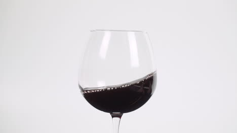 swirling red wine in burgundy glass