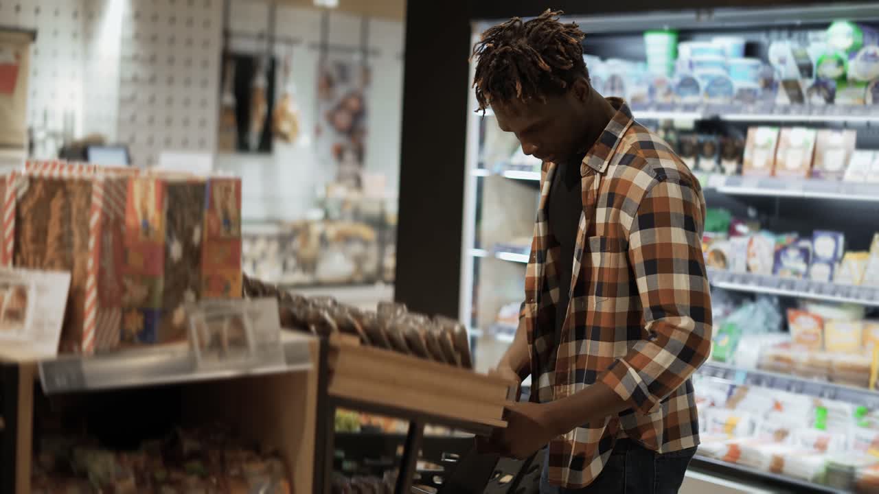 Male customer chooses smth in the grocery store from the shelf