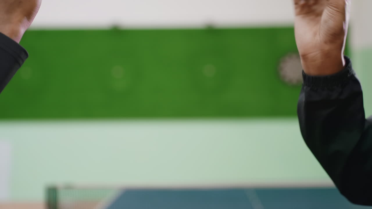 Close up of two friends raising fists while playing engaging hand trick game near indoor tennis table, capturing playful gesture, energy, and concentration in friendly competition